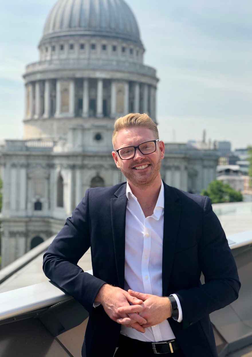 Dan in a suit on a rooftop in the City of London